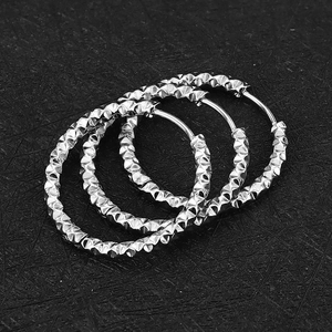 Detailopname van drie zilveren titanium oorbellen met ruitvormige patronen