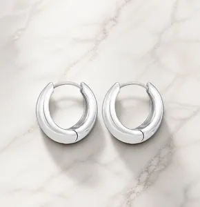 Detailed view of thick silver crescent hoop earrings with high-polished mirror finish