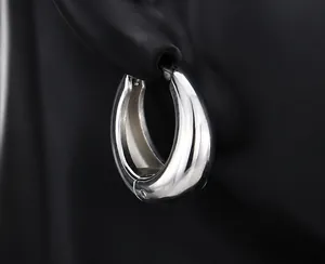 Detailed close-up of polished silver teardrop hoop earrings on a black display model