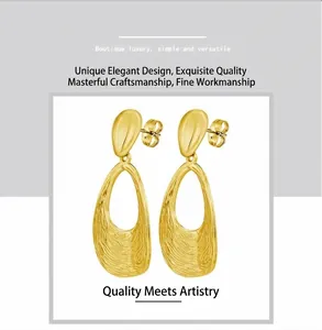 Detail shot of golden drop earrings featuring textured wavy hollow pendants and sleek studs