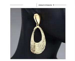 Macro shot of large golden hollow oval earrings with irregular hammered texture on model