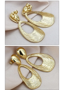 Detailed view of large gold hollow oval earrings with unique rippled texture surface