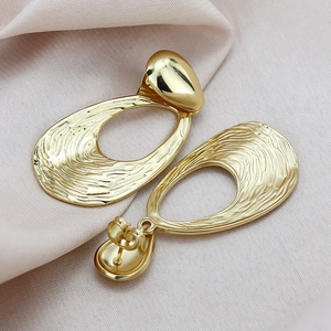 Elegant gold drop earrings with irregular hollow design and polished oval stud on silk cloth