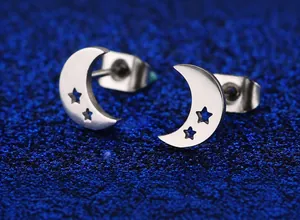 Vue macro détaillée de boucles d'oreilles lune et étoile en acier inoxydable argenté sur bleu