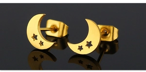 Vue macro des boucles d'oreilles lune et étoile dorées avec reflet miroir poli