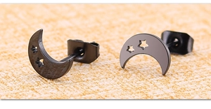 Gros plan détaillé des clous d'oreilles lune et étoile noirs mats avec motifs ajourés