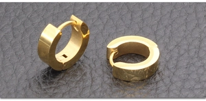 Vista detallada de pendientes de aro minimalistas en acero de titanio dorado sobre cuero