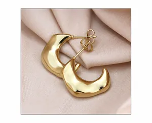 Detailed view of crescent moon C-shape gold earrings on pink silk background