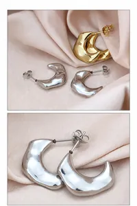 Detailed close-up of gold and silver crescent moon C-shaped stud earrings on champagne satin