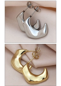 Macro detail of crescent moon stud earrings in polished gold and silver finishes