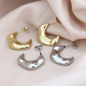 Chunky crescent hoop earrings in gold and silver finish on soft silk fabric