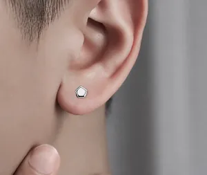 Macro view of a silver geometric pentagon stud earring worn on a male model's ear