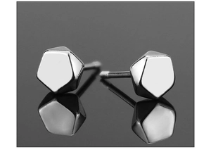 Macro shot of geometric pentagonal silver stud earrings with high-polish metallic finish