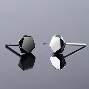 Macro detail of 6mm geometric faceted stud earrings in silver and black metal