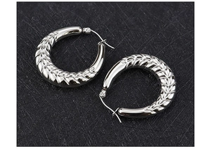 Vue macro de boucles d'oreilles créoles en acier argenté avec relief en épi de blé