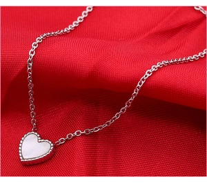 Detail van zilveren hartketting met parelmoer inleg en parelrand op rode stof