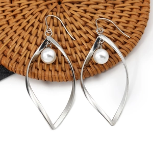 Elegante bladvormige zilveren metalen oorbellen met witte parels op een gevlochten mat