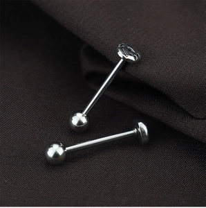 Vue macro de piercings de langue en acier argenté avec motifs crâne évidé et sphère