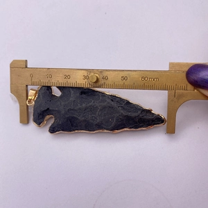 Gedetailleerde meting van de pijlpunt steenhanger met gouden rand en zwarte minerale textuur