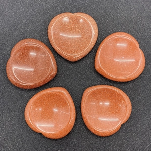 Macro view of five heart-shaped goldstone thumb stones with shimmering glitter effect
