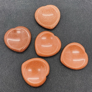 Macro shot of five heart-shaped goldstone beads with shimmering red-brown texture