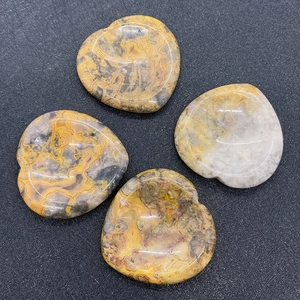 Macro shot of four polished heart-shaped agate stones with natural yellow and grey textures