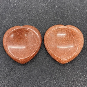 Macro view of heart-shaped goldstone worry stones with sparkling texture and concave design