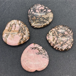 Detailed view of four heart-shaped polished rhodonite worry stones with natural black veins