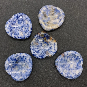 Vue détaillée de cinq pierres de pouce en sodalite bleue en forme de cœur sur noir