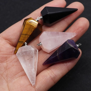 Detailed view of hand holding natural amethyst and tiger eye faceted cone pendants