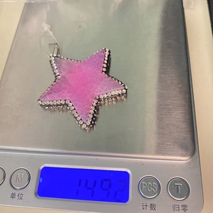 Pentagram star pendant with purple natural stone weighing 14.92g on a scale