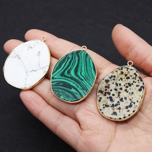 Macro shot of irregular natural stone pendants with gold metal edges held in hand
