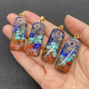 Macro shot of colorful resin stone pendants with metal spirals held in a hand for size