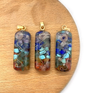 Chakra healing natural stone resin pendant with gold wire spiral on wooden plate
