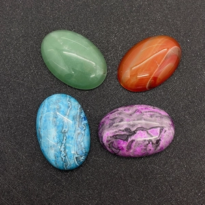 Close-up of four polished oval cabochon gemstones in green, orange, blue, and purple colors