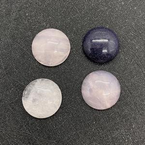 Close-up of polished 15mm round rose quartz and blue goldstone cabochons on a black board