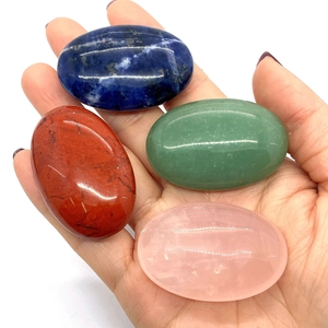 Hand holding four oval polished natural worry stones in jasper, aventurine, and quartz