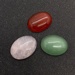 Macro detail of oval cabochon gemstones in rose quartz, aventurine, and carnelian