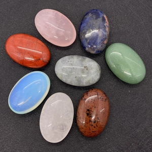 Collection of eight polished oval natural stones in varied colors on a black texture