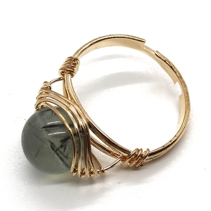 Détail d'une bague artisanale en fil doré avec perle de quartz rutilé noir naturel