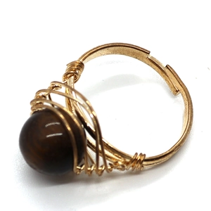 Macro d'une bague dorée faite main en fil métallique avec pierre œil de tigre polie