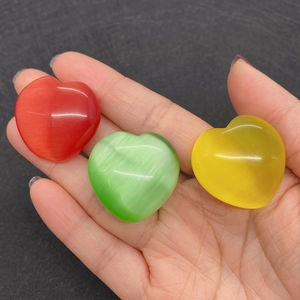 Tre pietre occhio di gatto a forma di cuore tenute in mano per mostrare le dimensioni