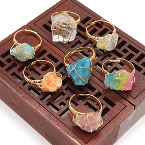 Handmade raw gemstone rings with wire wrap design on a wooden display box