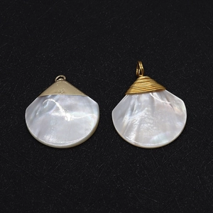 Pendentif en nacre naturelle en forme de goutte avec finition dorée sur fond noir