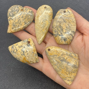 Dettaglio manuale di ciondoli in pietra naturale mista con trame uniche e fori preforati