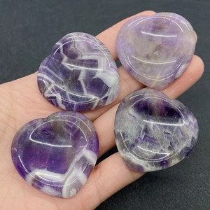 Vue macro de quatre cœurs en améthyste tenus à la main avec motifs naturels violets