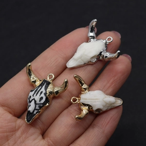 Detailed macro view of resin bull skull pendants with gold and silver electroplated edges