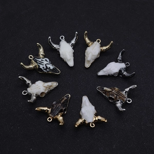 Overhead view of eight resin bull head pendants with assorted marbled textures and gold loops