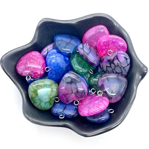 Détail de pendentifs en agate en forme de cœur dans un bol noir pour bijoux DIY