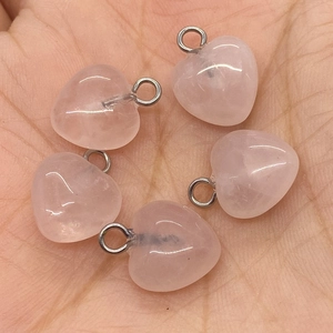 Cinque ciondoli a cuore in quarzo rosa con occhielli metallici presentati sulla mano